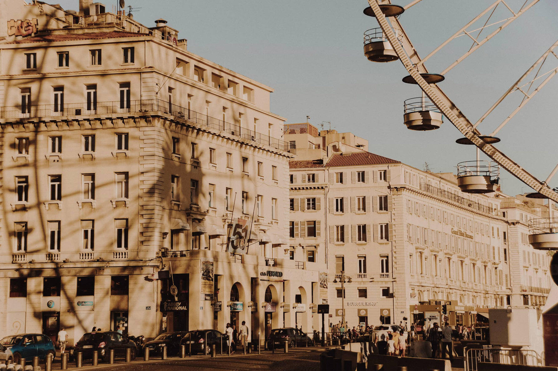 Part of a ferris wheel on the top right corner, with its shadow reflecting on the building across the street on the left side